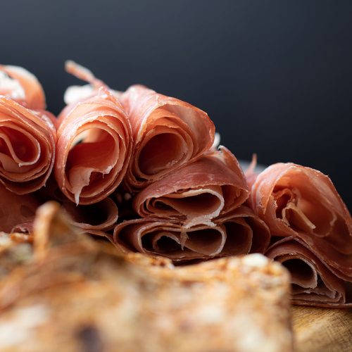 close up of prosciutto and crackers on a charcuterie meat board