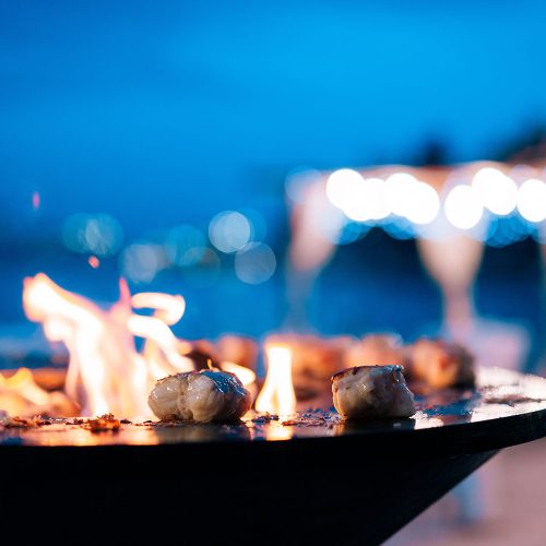 Close-up of pieces of fish fillet on a bowl-shaped grill with a fire hole in the center. . High quality photo